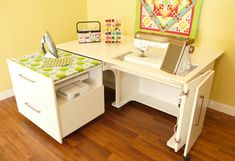 a white desk with a sewing machine on top of it next to a yellow wall