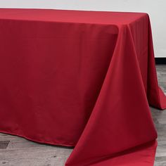 a red table cloth on top of a wooden floor in front of a white wall