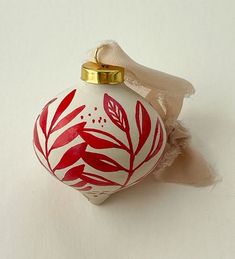 a red and white ornament with leaves on it