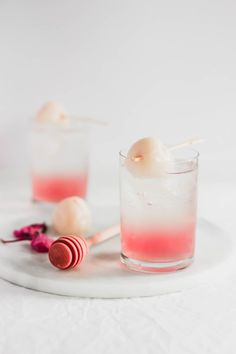 two glasses filled with ice cream sitting on top of a white plate next to candy