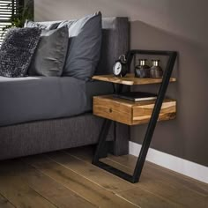 a bed sitting next to a wooden table on top of a hard wood floor