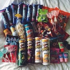 an assortment of candy and snacks laid out on a bed