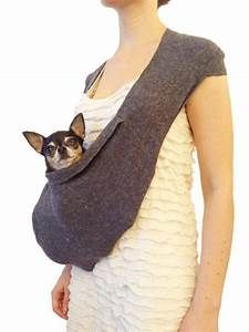 a woman holding a small dog in a sling