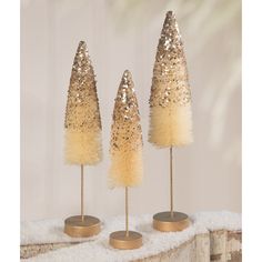 three gold and white christmas trees on top of snow