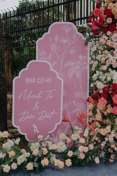 a sign that is next to some flowers and plants in front of a fence with the words nana go hy on it