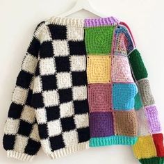 a multicolored sweater hanging on a white wall