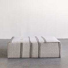 a black and white striped ottoman sitting on top of a cement floor next to a wall