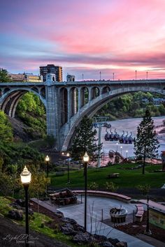 a bridge that is over some water and has lights on at the end of it