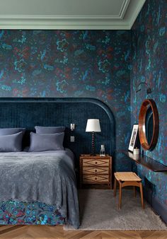 a bedroom with blue and green wallpaper, a wooden dresser and mirror in the corner