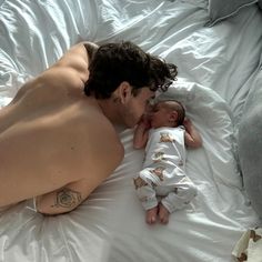 a man laying on top of a bed next to a small baby in a diaper