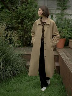 This trench coat is made of a sturdy blend of cotton and polyester for durability, exuding classic sophistication. It features a stand collar and contrasting detail for added interest.- Long length that makes your outfit stylish- Waist belt with buttons cinching the waistline for a feminine silhouette- Stitching details at the collar and sleeves as a refined touch Classic Khaki Outerwear With Belted Cuffs, Classic Khaki Belted Outerwear, Classic Outerwear With Stand Collar And Double Button Closure, Classic Brown Outerwear With Belted Cuffs, Korean Trench Coat Outfit, Korean Trench Coat, Beige Trench Coat Outfit, Contrast Outfit, Cotton Trench Coat