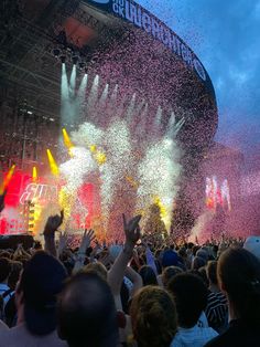 a large crowd is throwing confetti in the air at an outdoor music festival