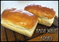 two white bread rolls sitting on top of a cooling rack with the words amish white bread