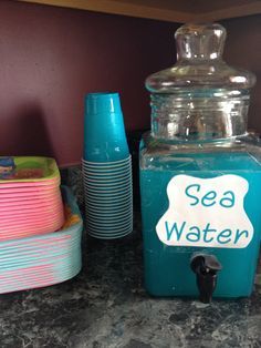 there are many plates and cups on the counter top, including one with sea water written on it