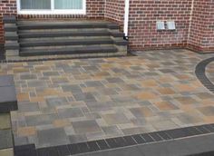 a brick patio with steps leading up to the front door