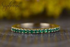 a close up view of a wedding band with green stones