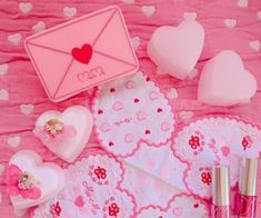 valentine's day items laid out on a pink tablecloth with hearts and envelopes