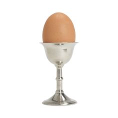 an egg in a silver cup on a white background with clippings to the side