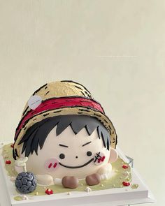 a cake shaped like a child's head on top of a white table with red and gold decorations