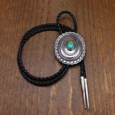 Vintage sterling silver and turquoise oval bolo tie. The center is domed and stamped. The silver is 2 3/4" tall x 2 1/4" wide. The turquoise is 17mm tall x 12mm wide. The cord and tips are 42" long. There is no maker's hallmark. The outside edge is scalloped. The bolo is in good condition. Thank you for shopping in our store. Please let us know if you have questions. BOLO-1293K k *The color you see on your screen may not reflect the actual stone color due to variations in monitors* Western Style Oval Engraved Jewelry, Western Oval Engraved Jewelry, Western Style Oval Concho Jewelry, Bohemian Silver Handmade Bolo Tie, Handmade Silver Bohemian Bolo Ties, Southwestern Silver Bolo Ties For Rodeo, Southwestern Silver Bolo Tie For Rodeo, Artisan Turquoise Bolo Ties With Concho, Vintage Turquoise Bolo Tie For Rodeo