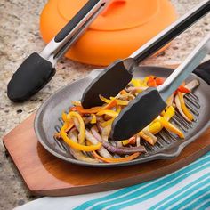 two tongs are being used to cut up food on a plate