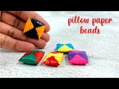 a hand holding some colorful paper beads on top of a white surface with the words pillow paper beads