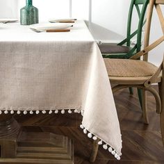 a table with a white table cloth on it and green chairs in front of the table