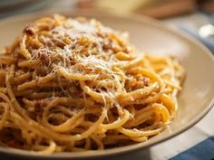 a white plate topped with pasta covered in parmesan cheese