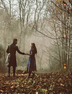 two people holding hands in the woods on a foggy day with trees behind them