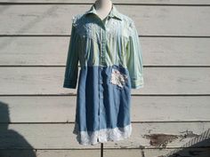 a blue and green shirt dress hanging on a wooden wall next to a mannequin