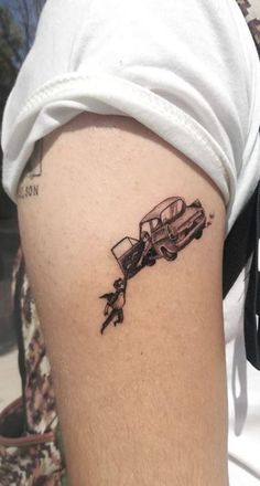 a man's arm with a tattoo on it that has a car coming out of the window