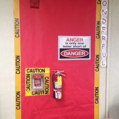 a red door with caution signs on it and a fire extinguisher next to it