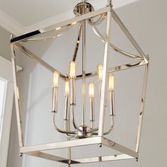 a chandelier hanging from the ceiling in a room with white walls and windows