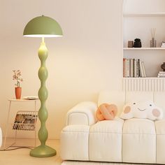 a living room with a white couch, green lamp and bookshelf in the background