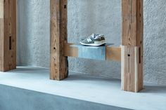 a pair of shoes sitting on top of a wooden bench in front of a concrete wall