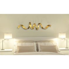 a bed with two lamps on either side of it and a wall hanging above the headboard