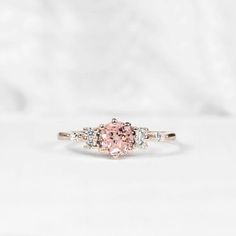 a pink and white diamond ring with three stones