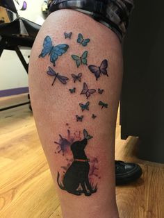 a woman's leg with butterflies and a dog tattoo on the side of her thigh