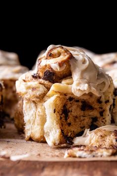 cinnamon roll with icing on top sitting on a cutting board