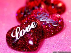 two red hearts with the word love written on them in white letters and glitters