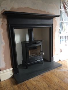 a wood burning stove sitting inside of a living room next to a wall with dry paint on it