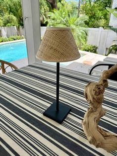 a table with a lamp on it and a pool in the back ground behind it