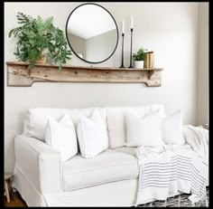 a living room with a white couch and mirror on the wall