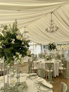 a banquet hall with tables and chairs covered in white draping, chandeliers and floral centerpieces