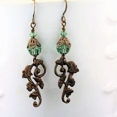 "An adorable new pair of crystal earrings with Swarovski crystals in a pretty pale emerald green, with a brass component with a gingko and ivy leaf pattern. These have a Victorian feel and are very lightweight! These one of a kind earrings measure 2 1/4\" and will arrive beautifully packaged. To see more jewelry and handmade beads, click here: https://www.etsy.com/shop/StoneDesignsbySheila?ref=hdr_shop_menu" Handmade Green Crystal Metal Earrings, Green Crystal Earrings For Jewelry Making, Vintage Green Czech Glass Earrings, Pierced Green Copper Earrings, Green Copper Pierced Earrings, Elegant Green Czech Glass Earrings, Elegant Green Copper Earrings, Green Beaded Metal Earrings, Green Dangle Jewelry With Bead Caps