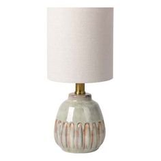 a ceramic lamp with a white shade on the top and gold trim around the base