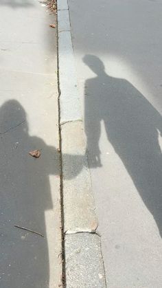 the shadow of a person riding a skateboard on a sidewalk next to a curb