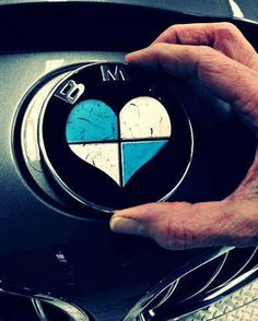 a man is holding the emblem on his bmw car's grill and steering wheel