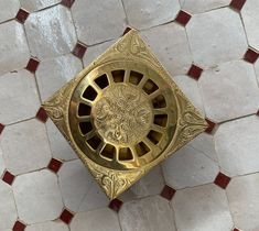 a golden square object sitting on top of a white and red tile floor