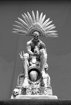 a statue is sitting on top of a pillar with an elaborate headdress above it